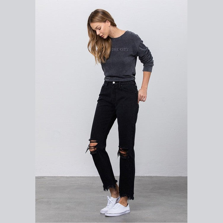 Trendy woman wearing edgy straight leg jeans with distressed details and a casual gray sweatshirt